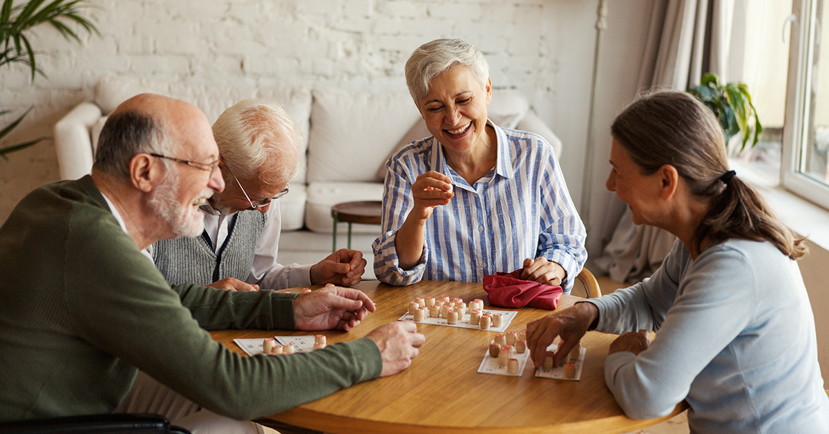 Group of seniors play game around table