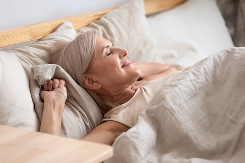 Older adult woman waking up in bed