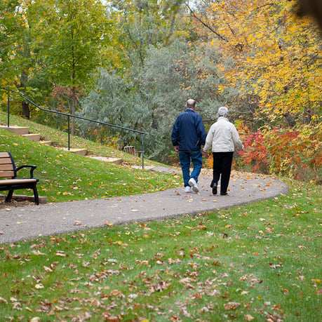 Senior couple walks on path holding hands during autumn