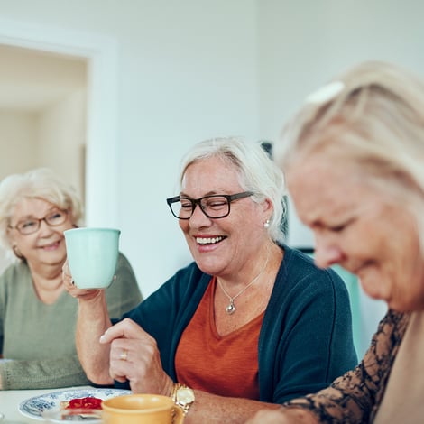 Senior women eat breakfast at table and drink coffee