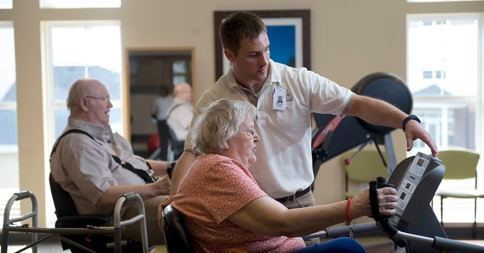 Seniors work out in senior living community with staff member