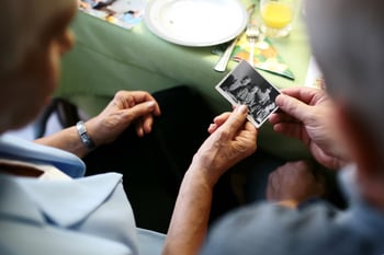 Elderly parent and child looking at an old photo