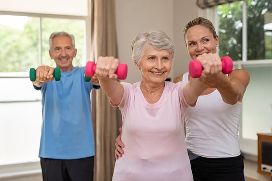 older couple working with trainer and lifting weights