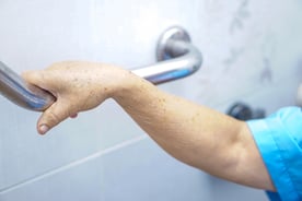 Senior grabbing hand rail in shower stall