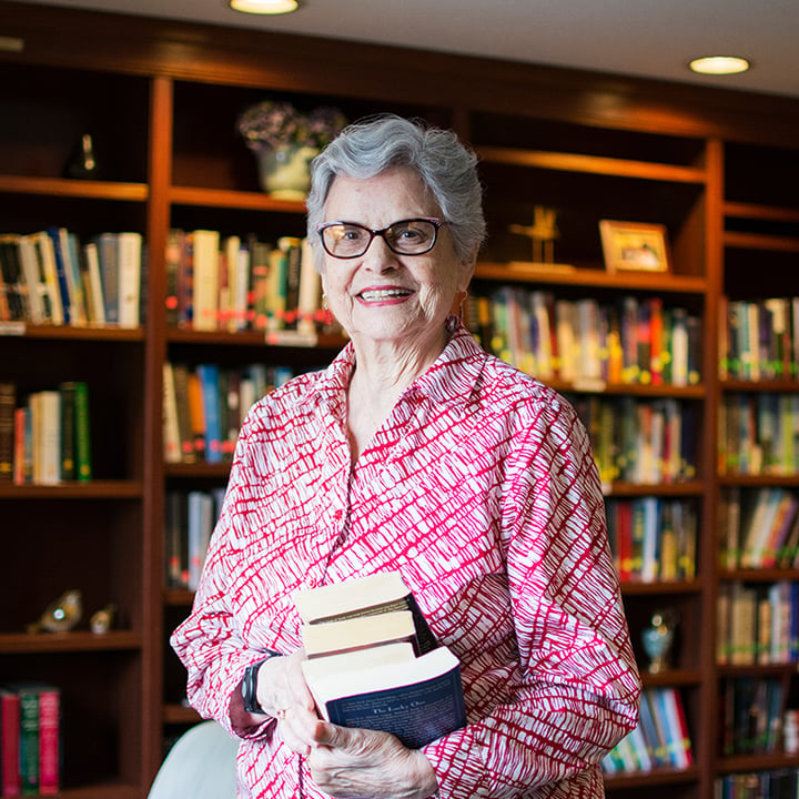 Elderly woman holding books in community library