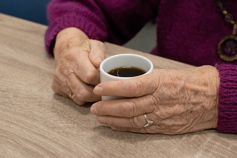 older woman holding coffee cup - close up on hands