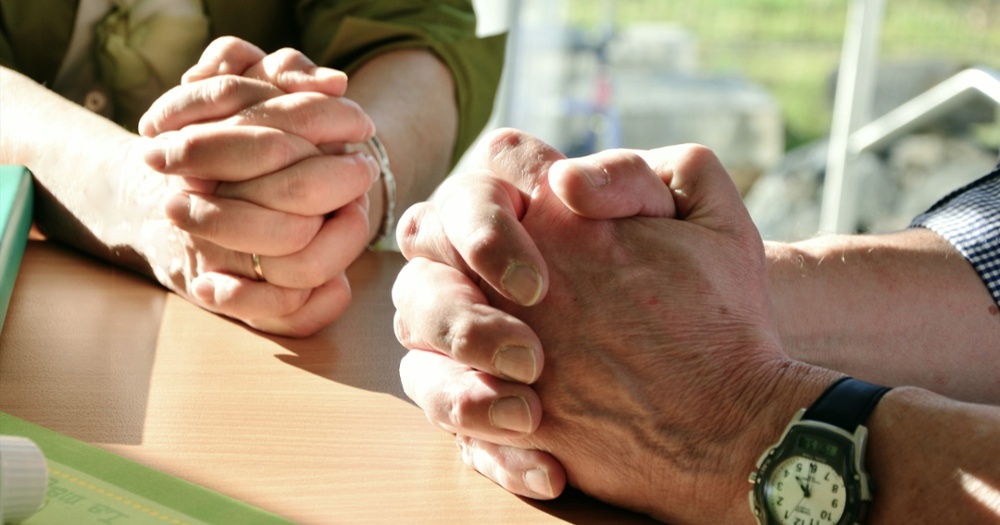 the hands of 2 people praying