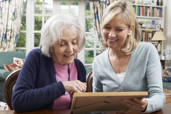 senior woman looking at picture with daughter