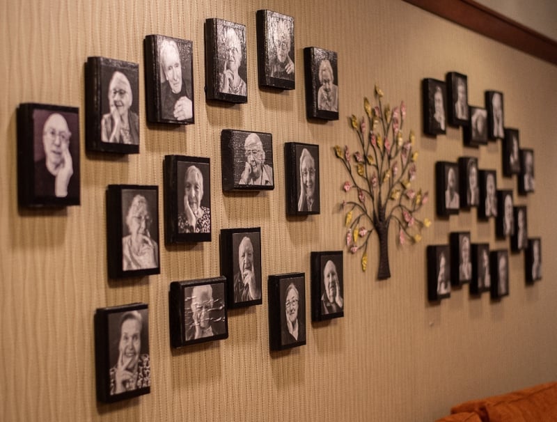 black and white photos of memory care residents hung in a group on a wall